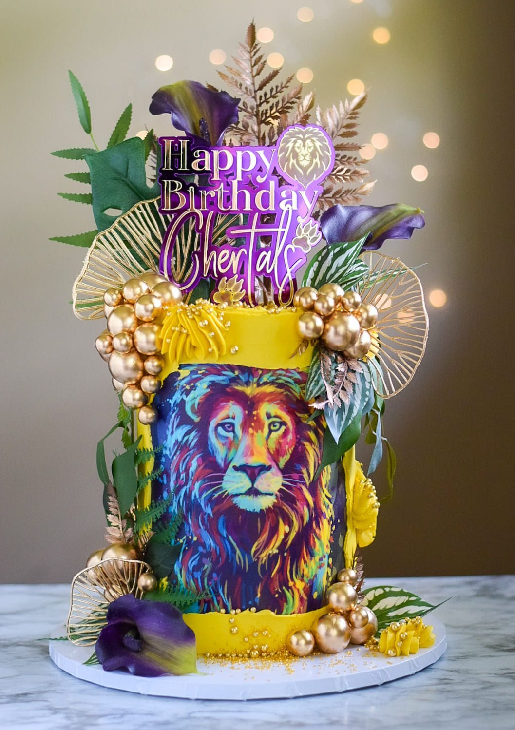 Colorful birthday cake with lion art and gold and purple decorations.