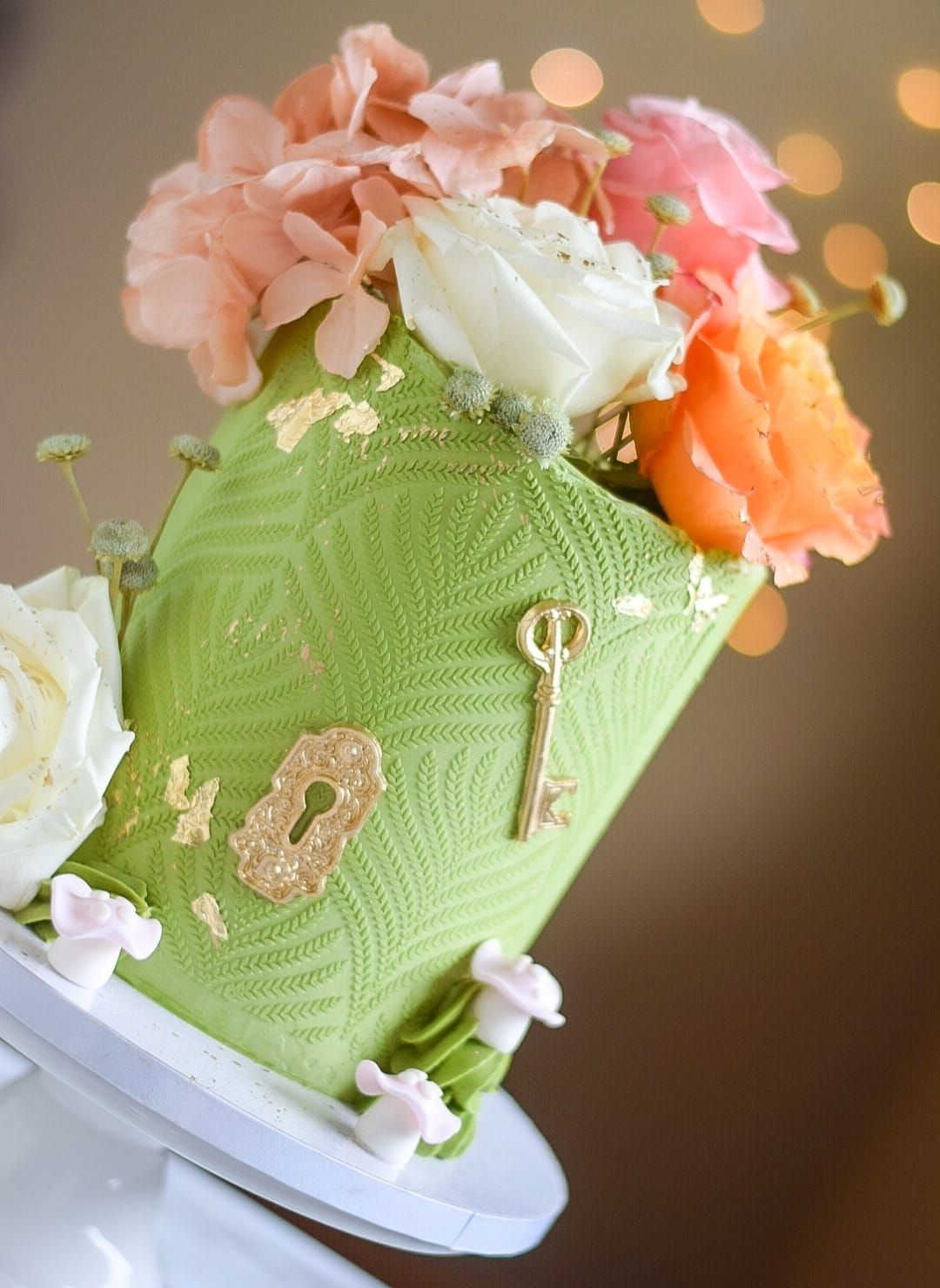 Green hat-shaped cake decorated with gold accents and colorful flowers.