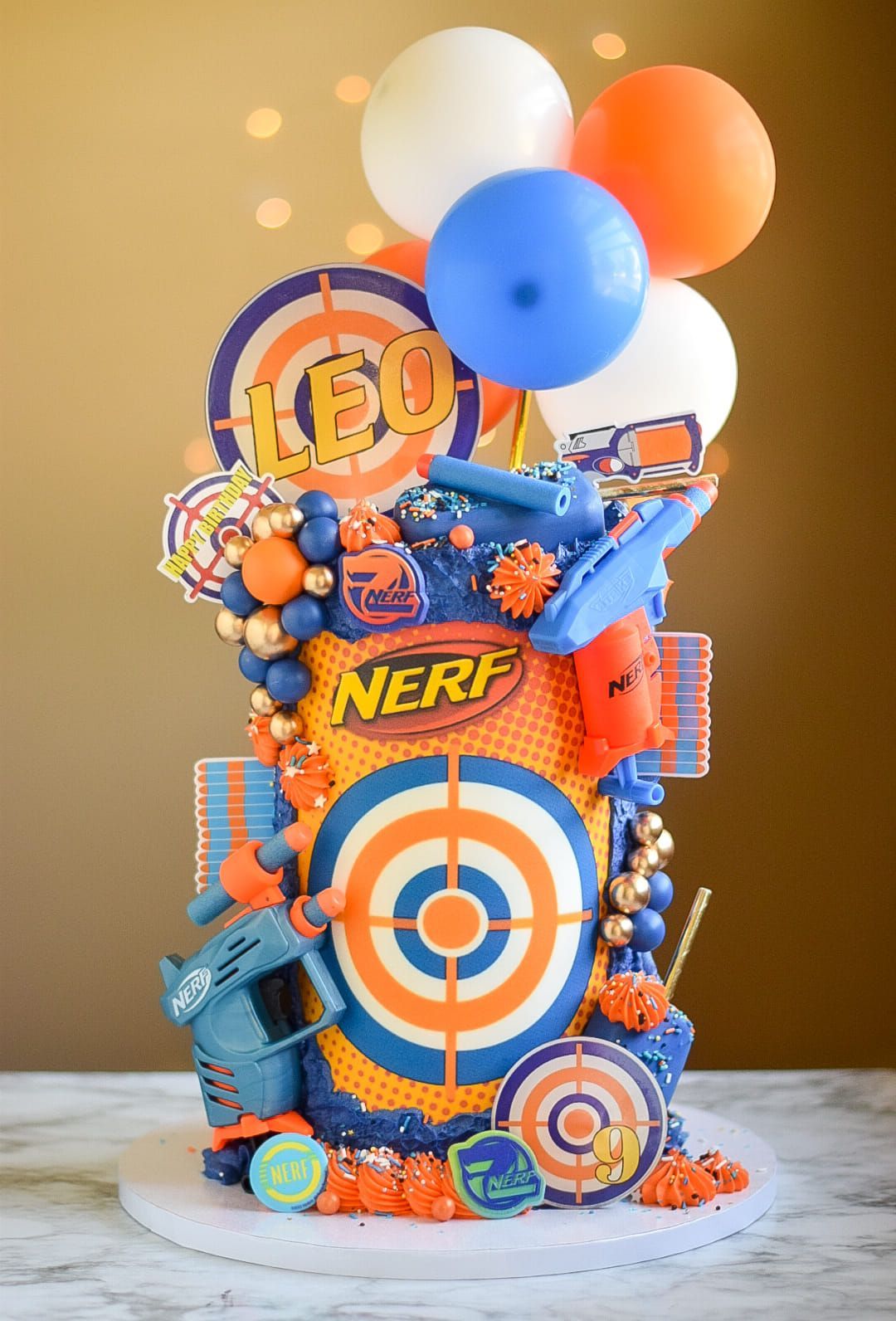 Nerf-themed birthday cake with balloons, target designs, and Nerf logo.