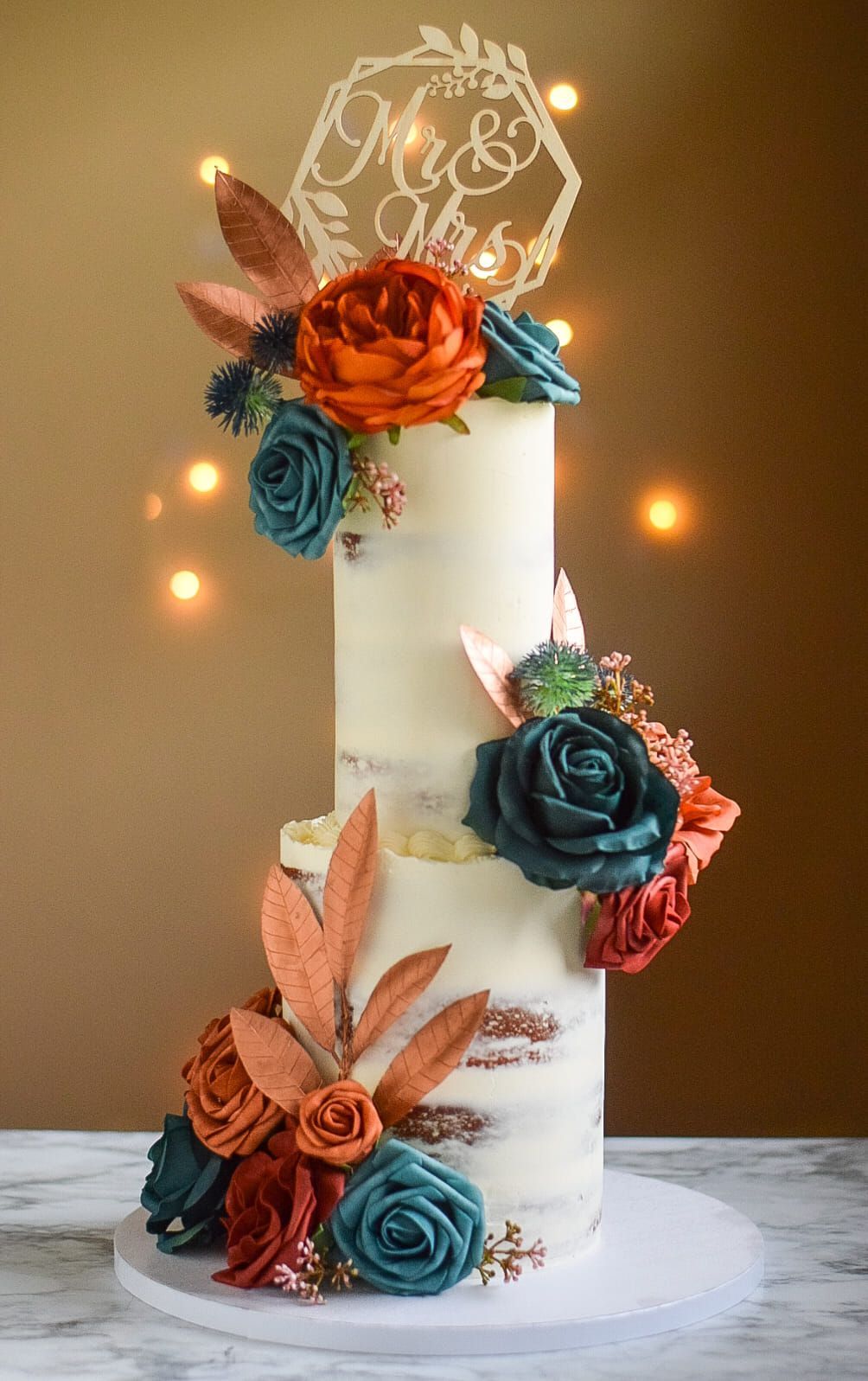 Two-tiered wedding cake with teal and orange flowers, 