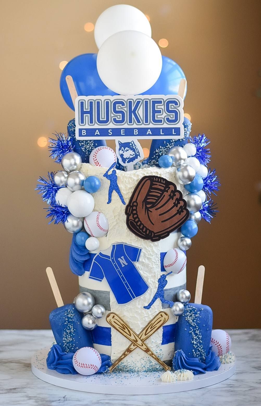 Baseball-themed cake with blue and white decorations, including baseballs, a glove, and 