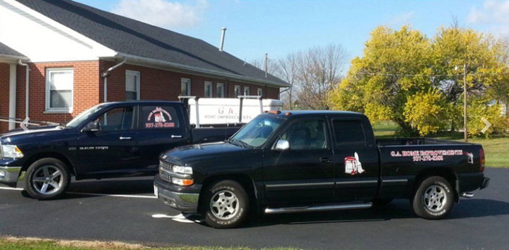 Two black pickup trucks parked outside a brick building on a sunny day