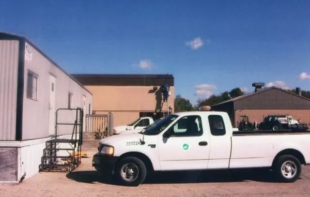 White pickup truck parked beside beige buildings on a sunny day
