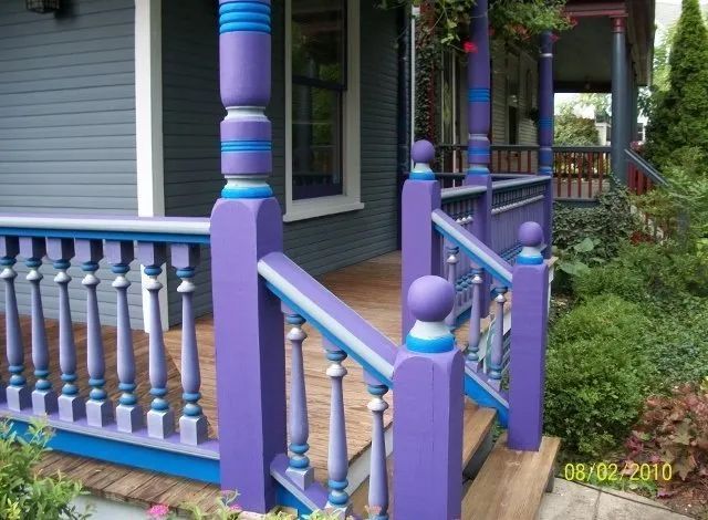 Colorful purple and blue porch railings on a house with steps and a wooden deck