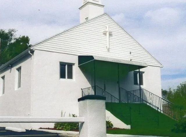 White church building with a green ramp and stairway under a small steeple