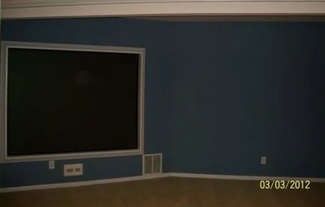 Empty room with blue walls, a large blackboard on the left, and a date stamp in the corner.