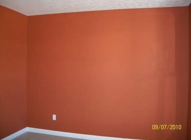 Empty room with orange walls, white trim, and carpeted floor