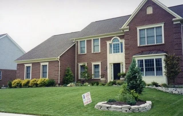 Large brick suburban house with a manicured lawn and landscaped front yard