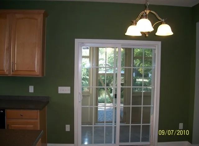 Kitchen with green walls, wooden cabinets, and a sliding glass door to a backyard.