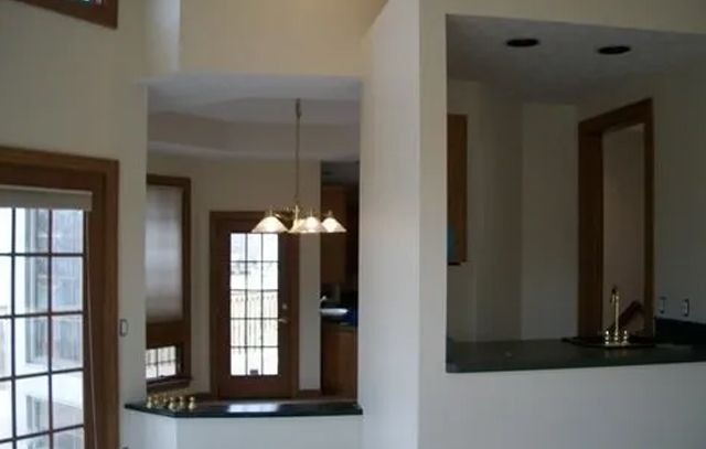 Empty kitchen pass-through and dining area with white columns and dark wood trim