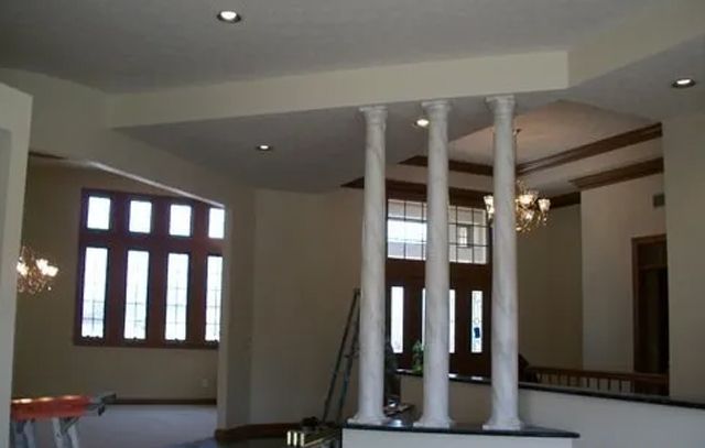 Bright interior room with white columns, arched windows, and recessed ceiling lights