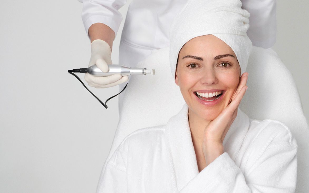 Eine Spa-Therapeutin hält eine Gesichtsmaske neben einer lächelnden Kundin in weißen Bademänteln und Handtüchern.