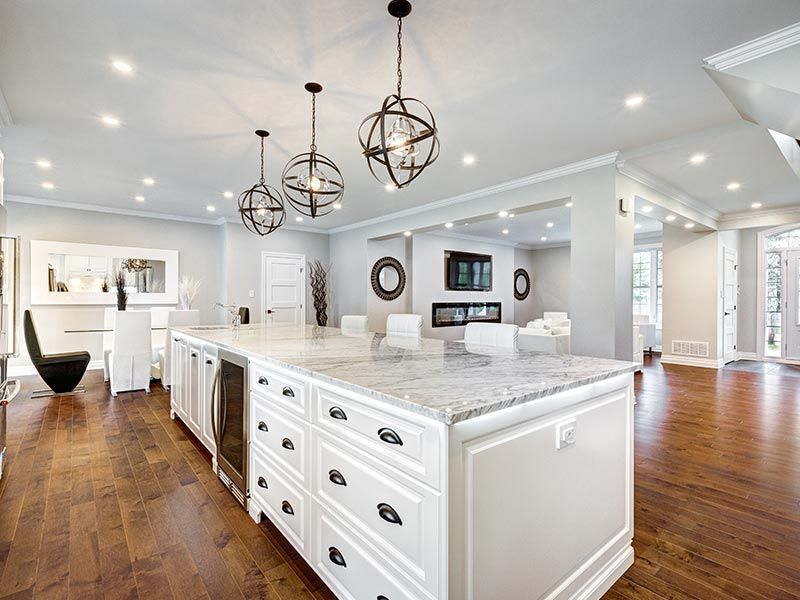 Bright white kitchen with marble island, pendant lights, and hardwood floors in an open-concept home