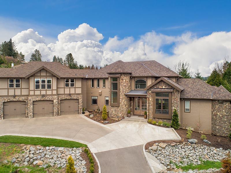 A large house with a lot of garages is sitting on top of a hill.