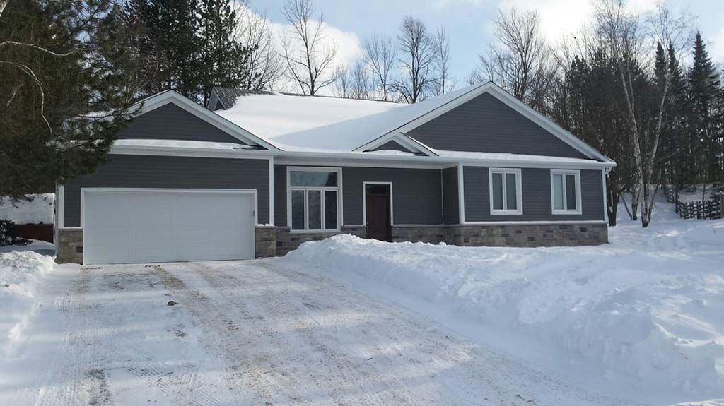 A house with a garage is covered in snow.