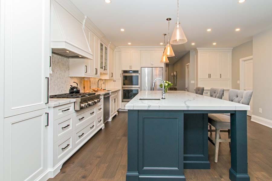 A kitchen with white cabinets and a large island in the middle.