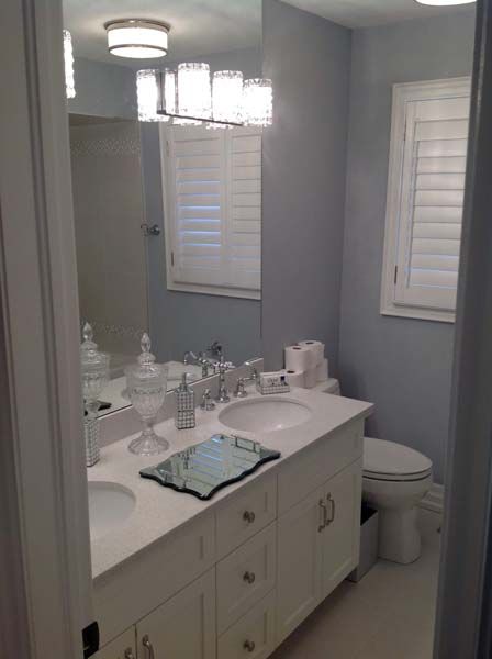 Small gray bathroom with white vanity, mirror, window, and light fixture.