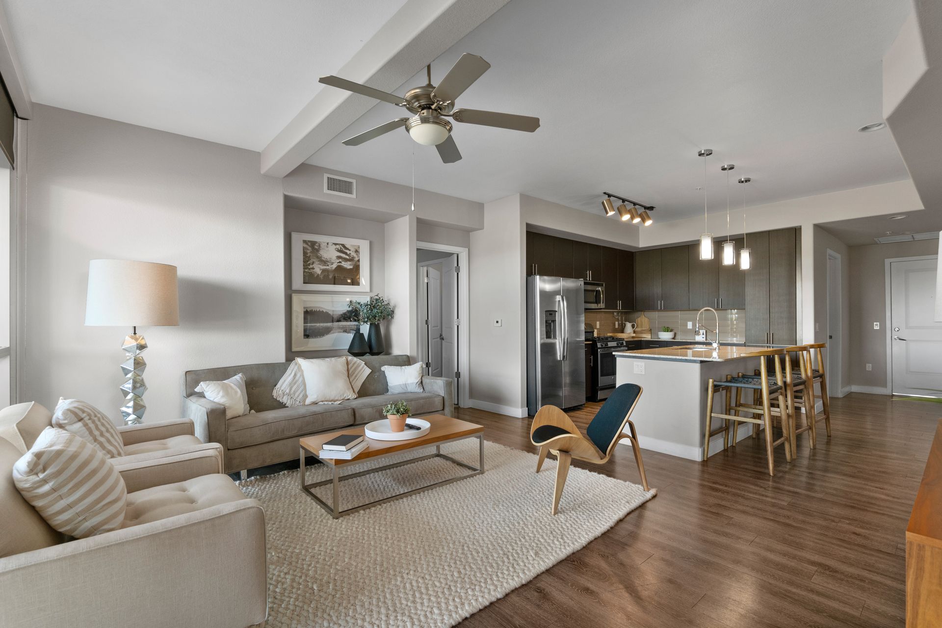 Living room with a sofa, armchair, and kitchen with a breakfast bar.