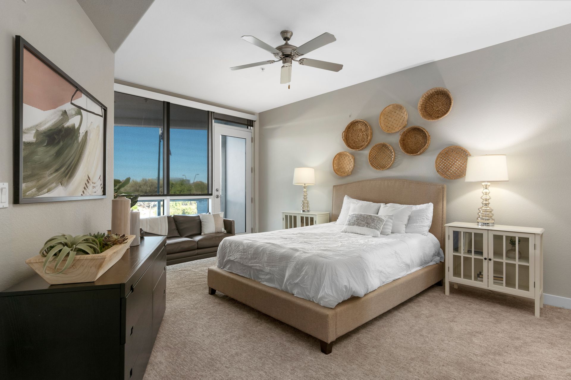Bedroom with bed, dresser, and window, decorated in neutral colors, with art and woven wall decor.