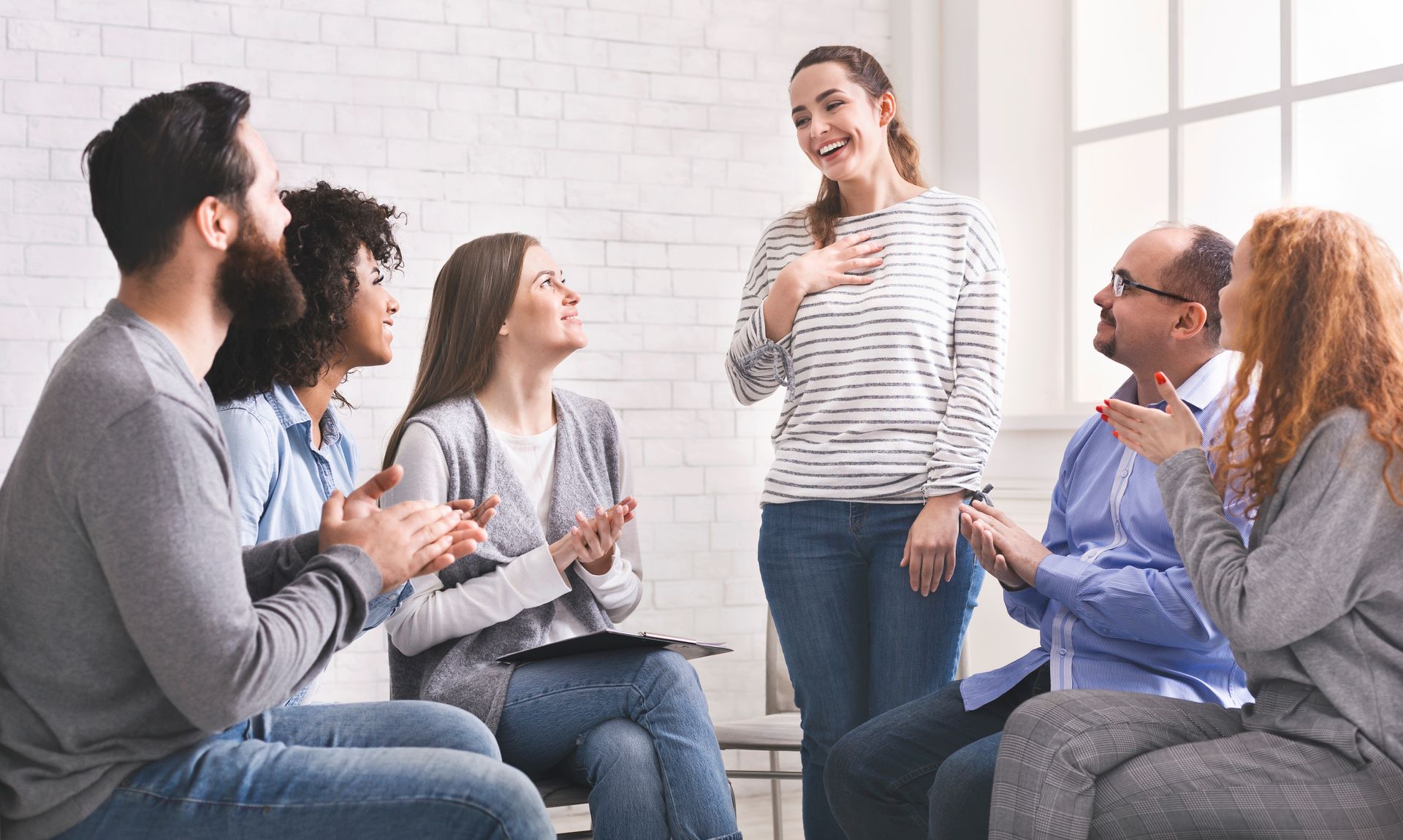 A group of people are sitting around a table talking to each other.