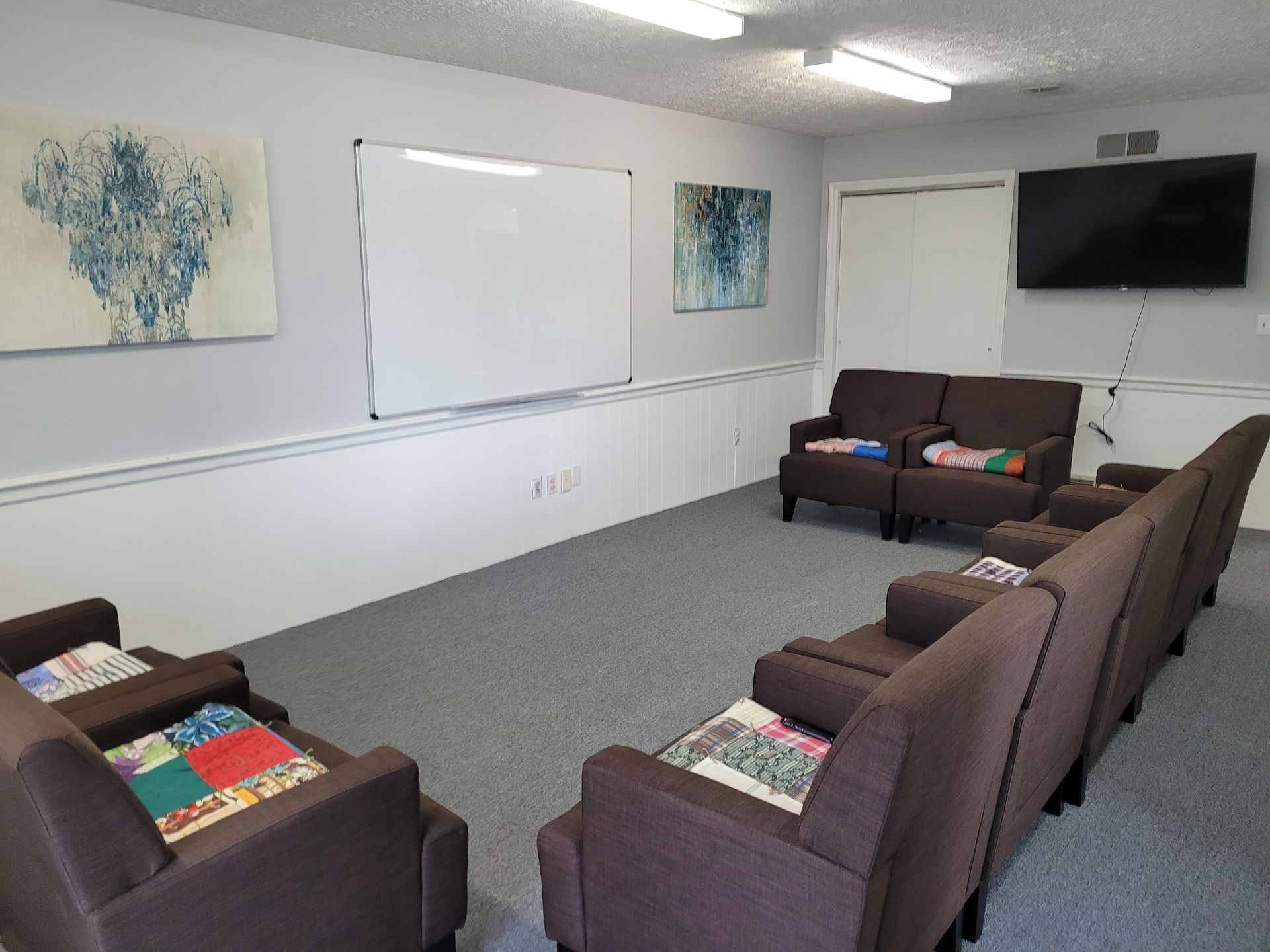 A room with a lot of chairs and a television on the wall.