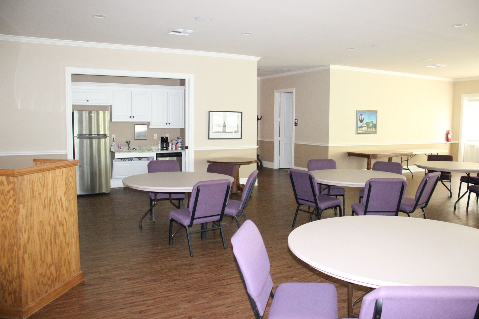 A large room with tables and chairs and a refrigerator