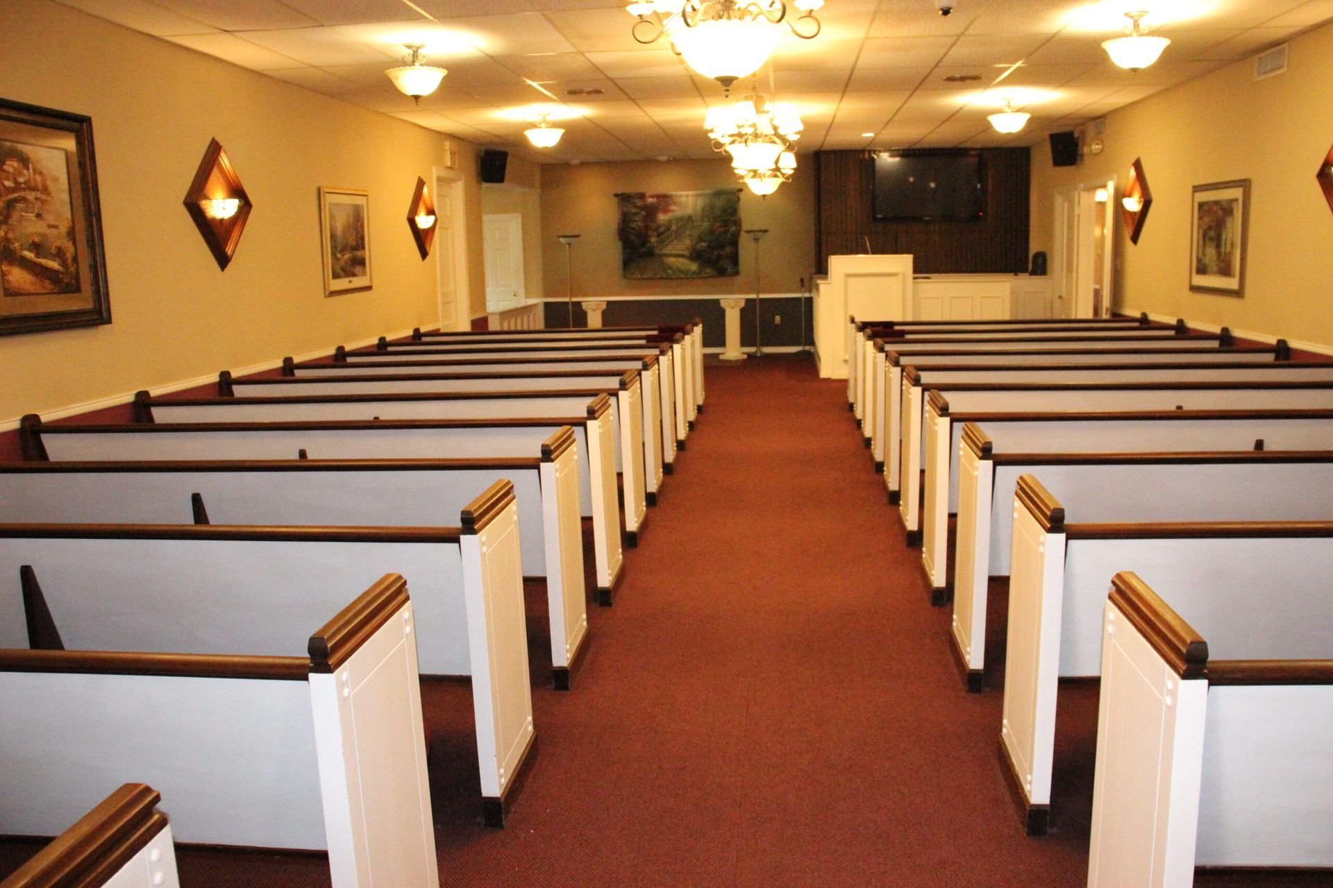 Rows of white benches in a church with a red carpet