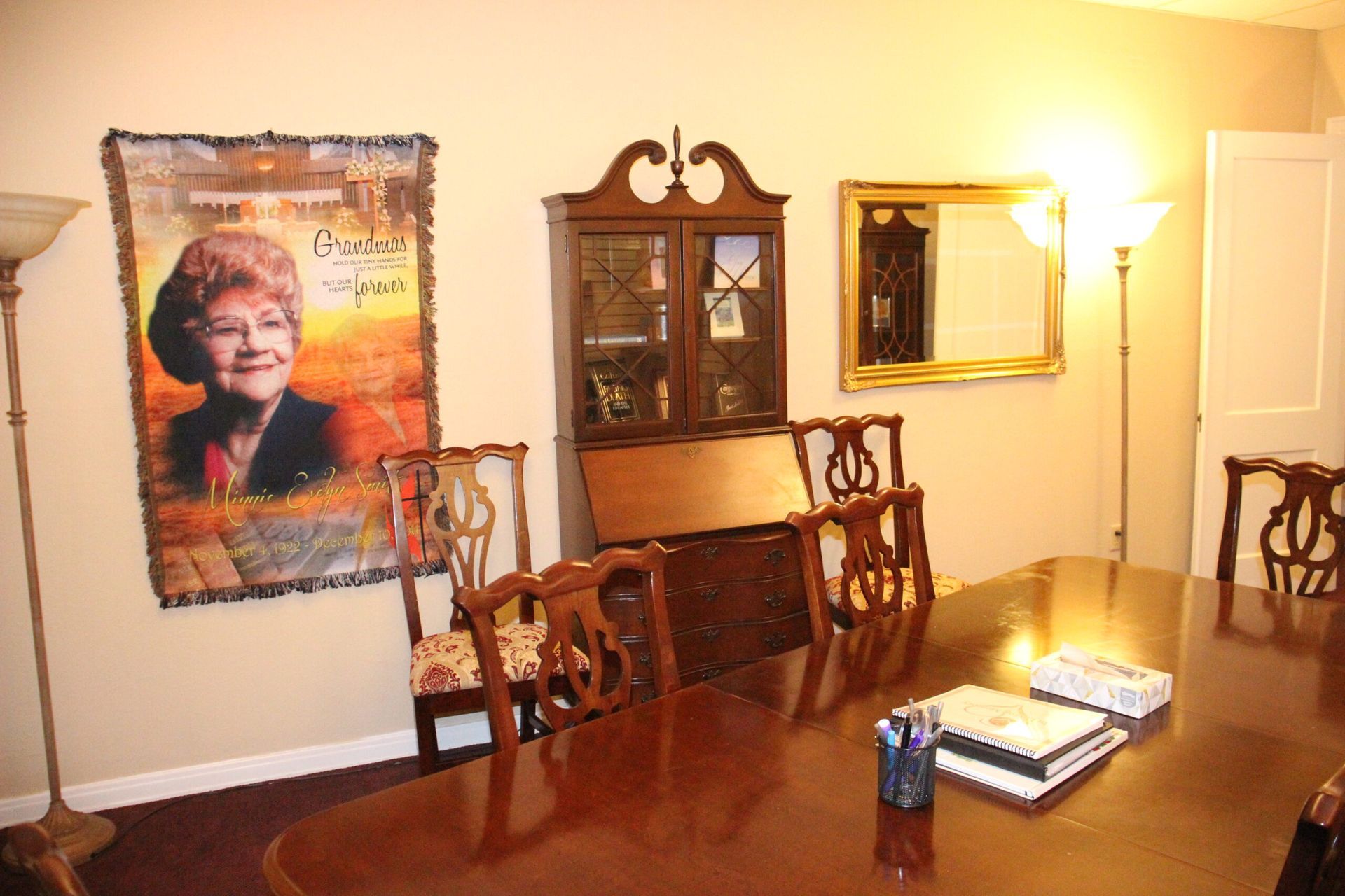 A room with a table and chairs and a picture of a woman on the wall