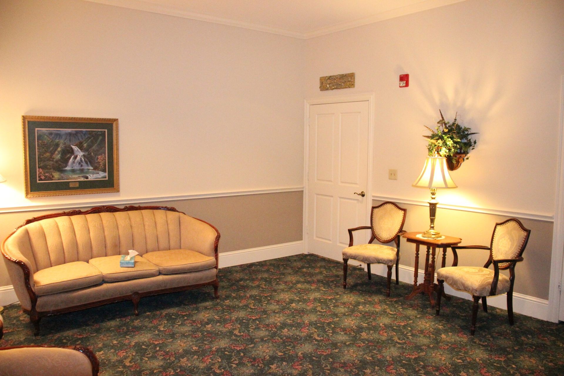 A living room with a couch and chairs and a painting on the wall