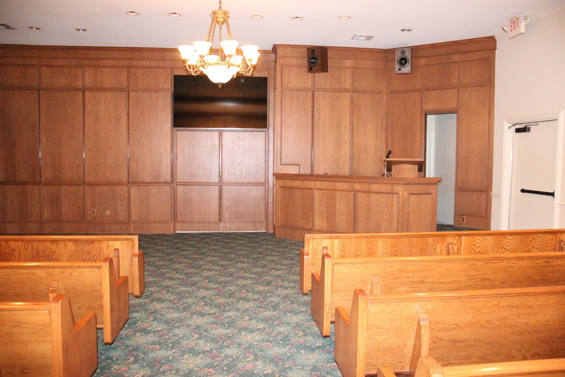 An empty church with wooden benches and a chandelier