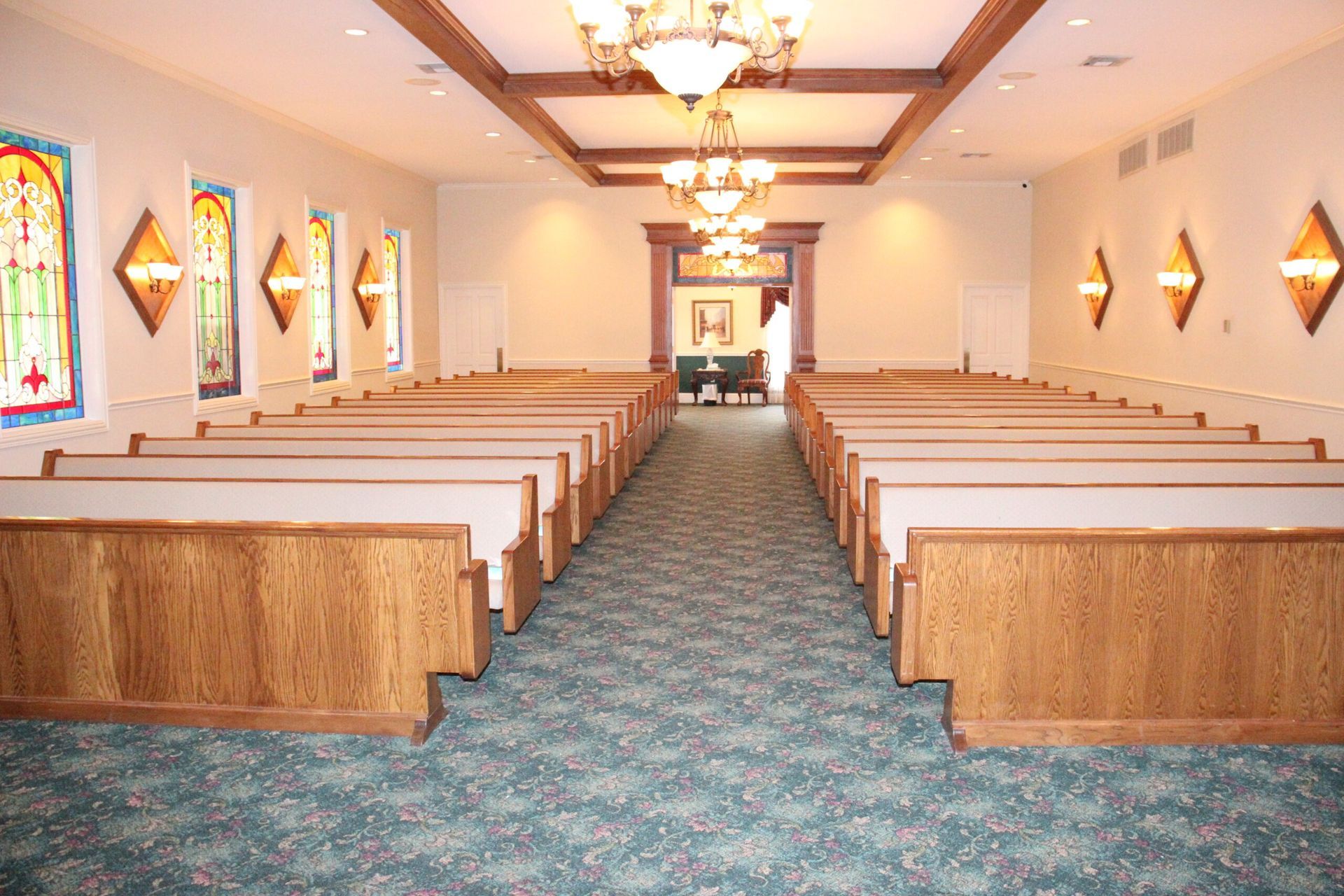 A church with rows of wooden benches and stained glass windows.