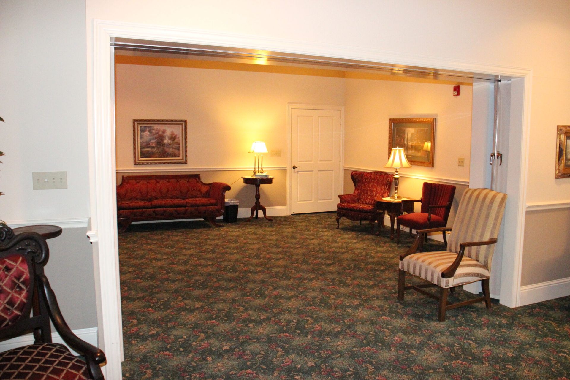 A living room with a couch , chairs , tables and lamps.
