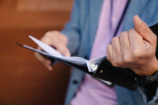 Person in a blue suit writes in a notebook with a black pen