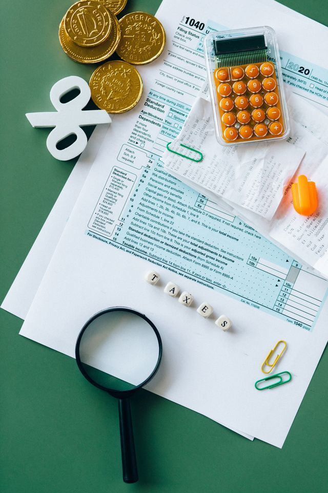 Budgeting and finance tools on a white desk: calculator, coins, bills, magnifier, paper clips, and pills.