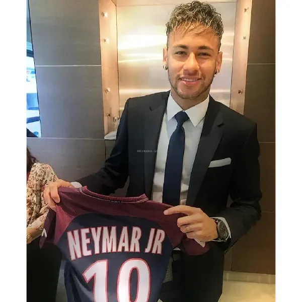 A man in a suit and tie is holding a jersey that says neymar jr 10