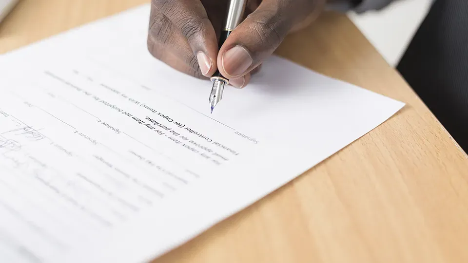 A person is writing on a piece of paper with a pen.