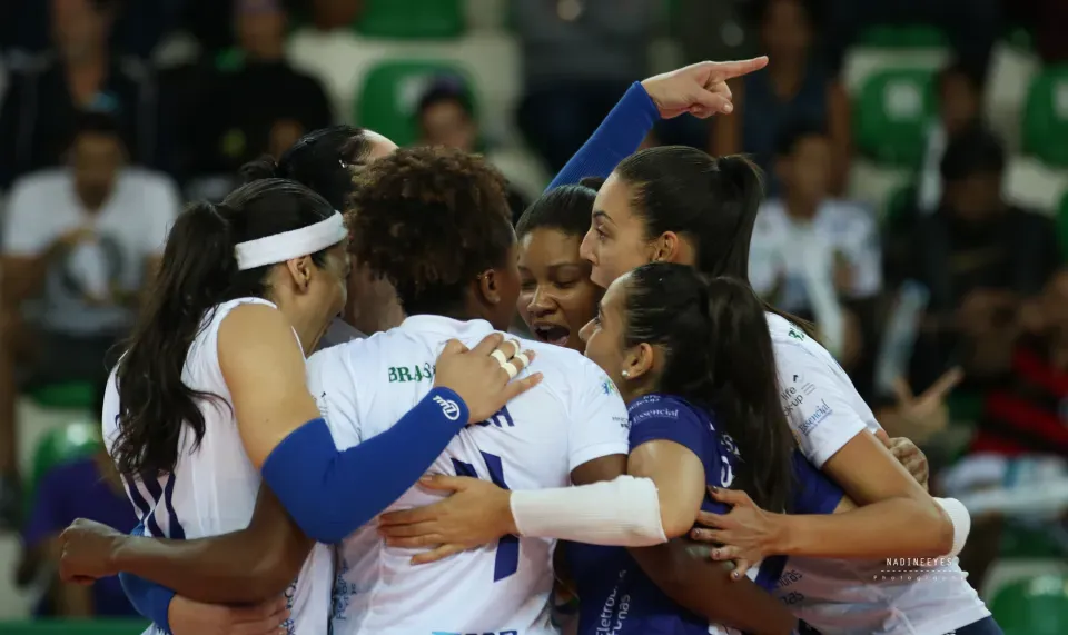A group of volleyball players are hugging each other on the court.
