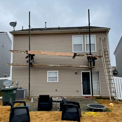 A house with scaffolding on the side of it and chairs in front of it.