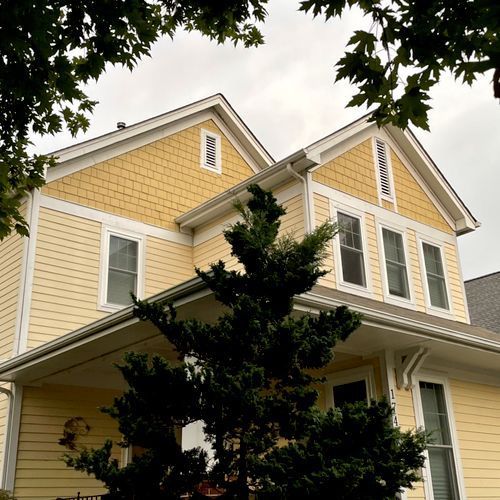 A yellow house with a tree in front of it