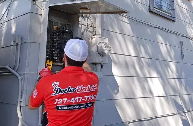 Worker in red shirt inspecting exterior wall and metal awning on a house.