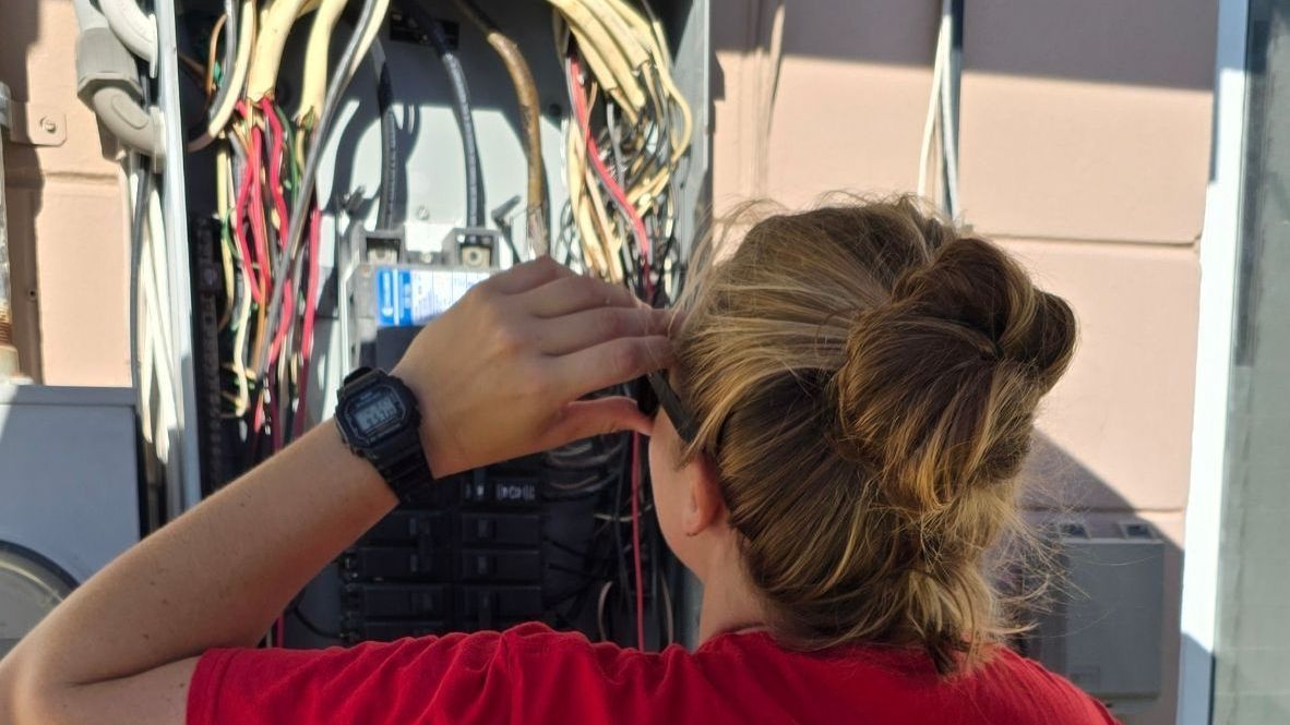 Technician inspecting electrical wiring in an open panel outdoors