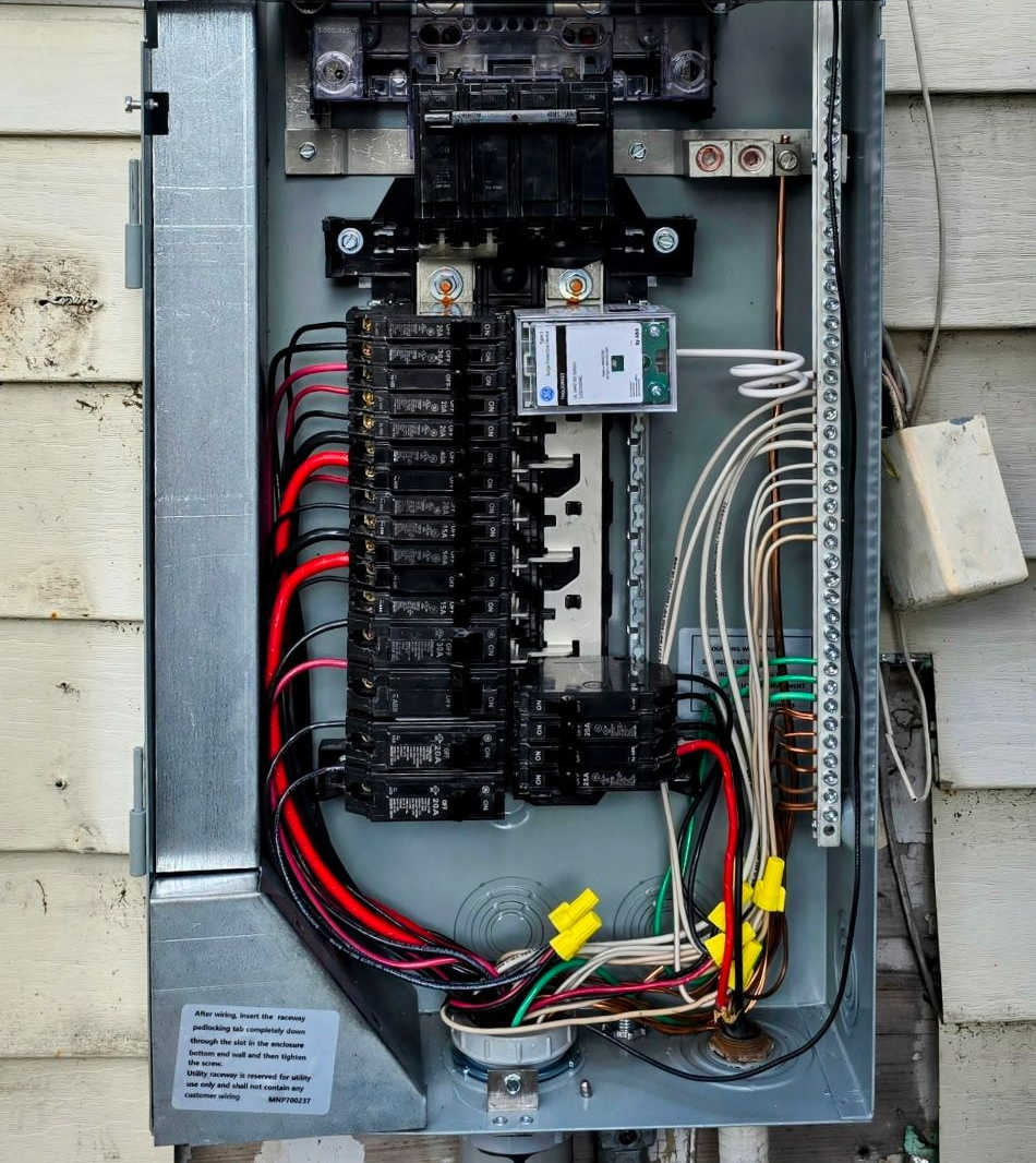 Open electrical breaker panel with black switches, red and white wires, and exposed wiring inside a metal box