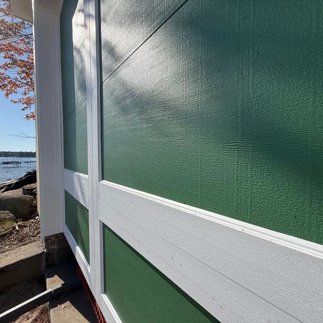 Green and white exterior wall panels beside a waterfront walkway in bright sunlight