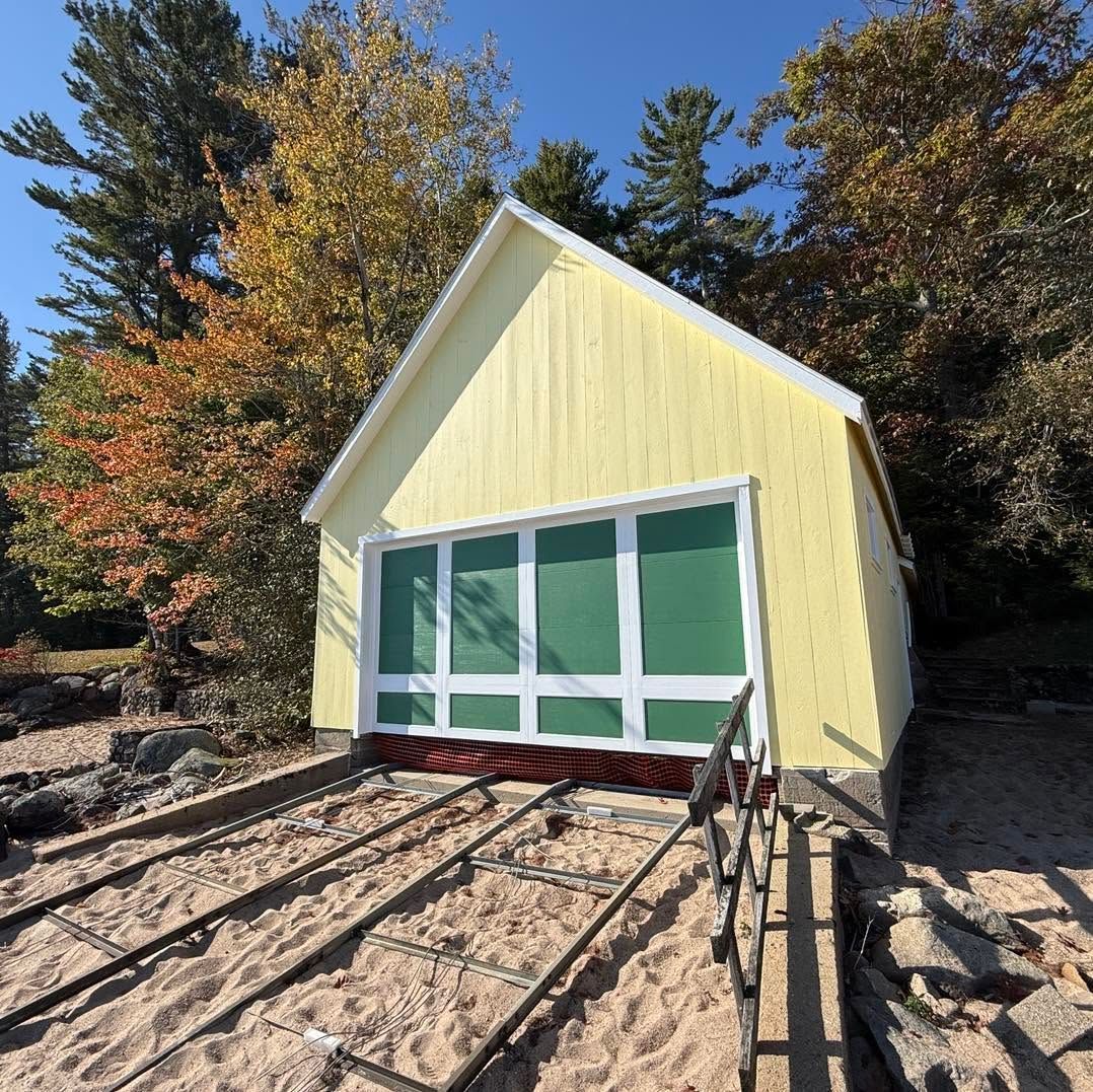 Yellow A-frame cabin with green-trimmed windows in a rocky, wooded setting