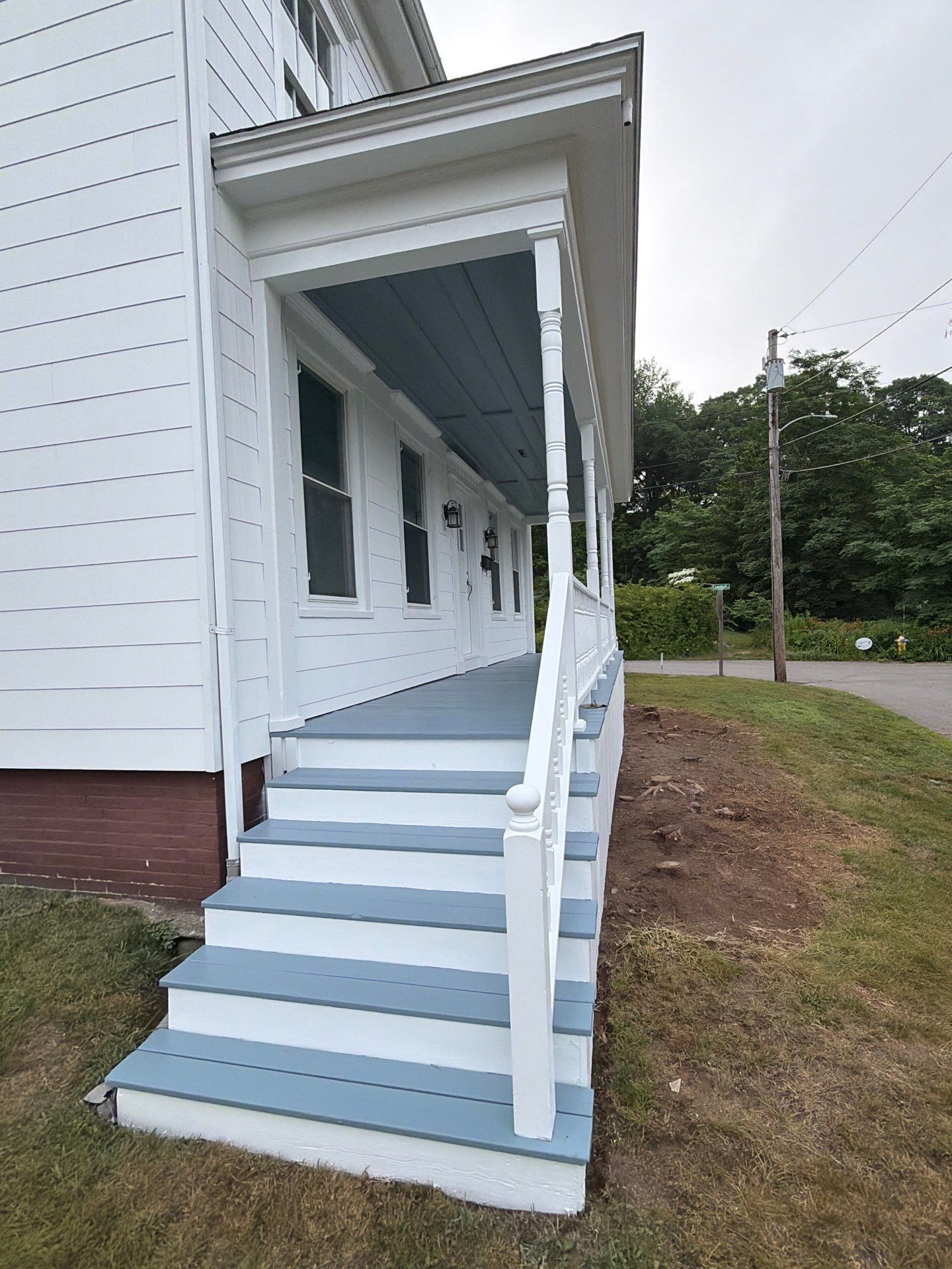 White house porch with light blue steps and white railing leading to a covered entrance