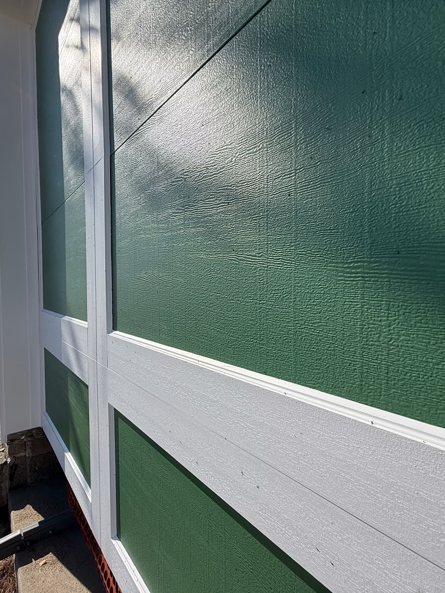 White-framed frosted glass panels beside a green wall in a narrow outdoor corridor