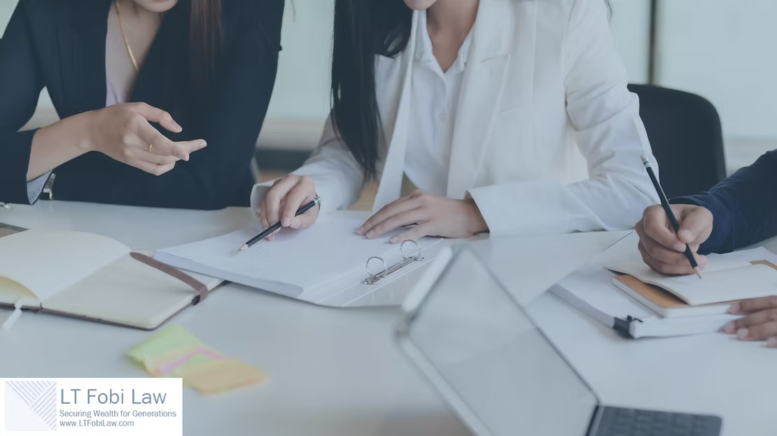 People in business attire reviewing documents and writing at a conference table in a meeting room
