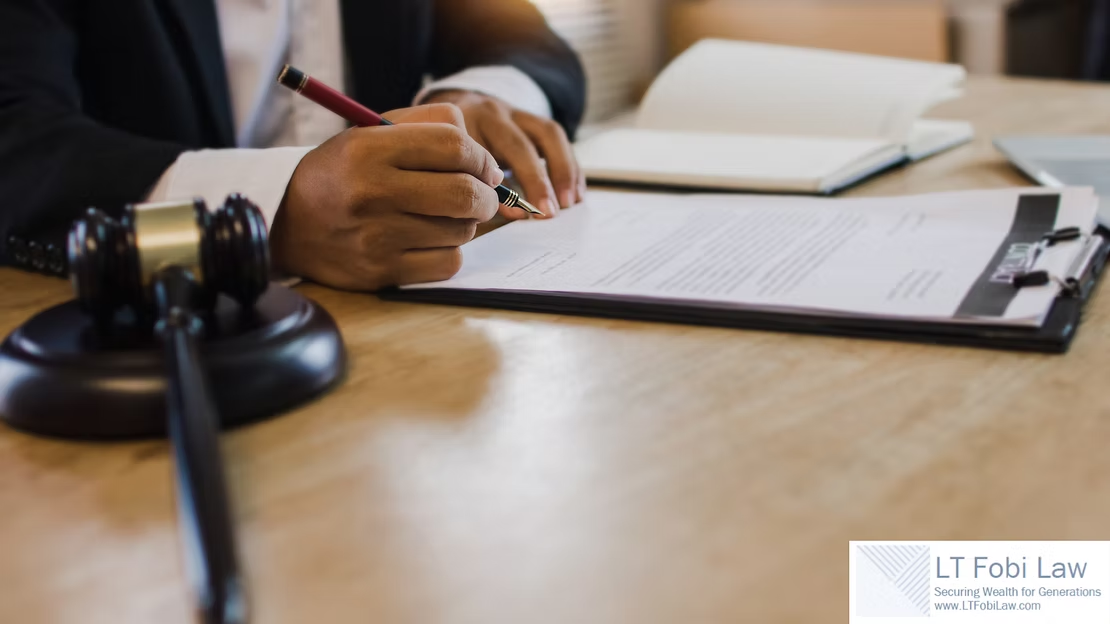 Hand signing a document on a clipboard beside a judge’s gavel on a wooden desk