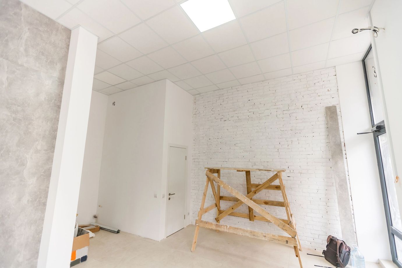 Bagno parzialmente ristrutturato con pareti piastrellate, mobili bianchi e un cavalletto di legno al centro.