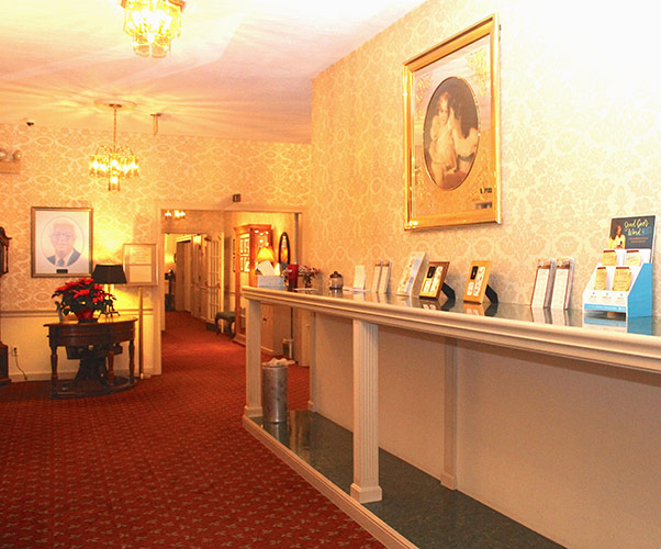 Elegant hotel lobby with red carpet, warm lighting, reception desk, and framed art on cream walls